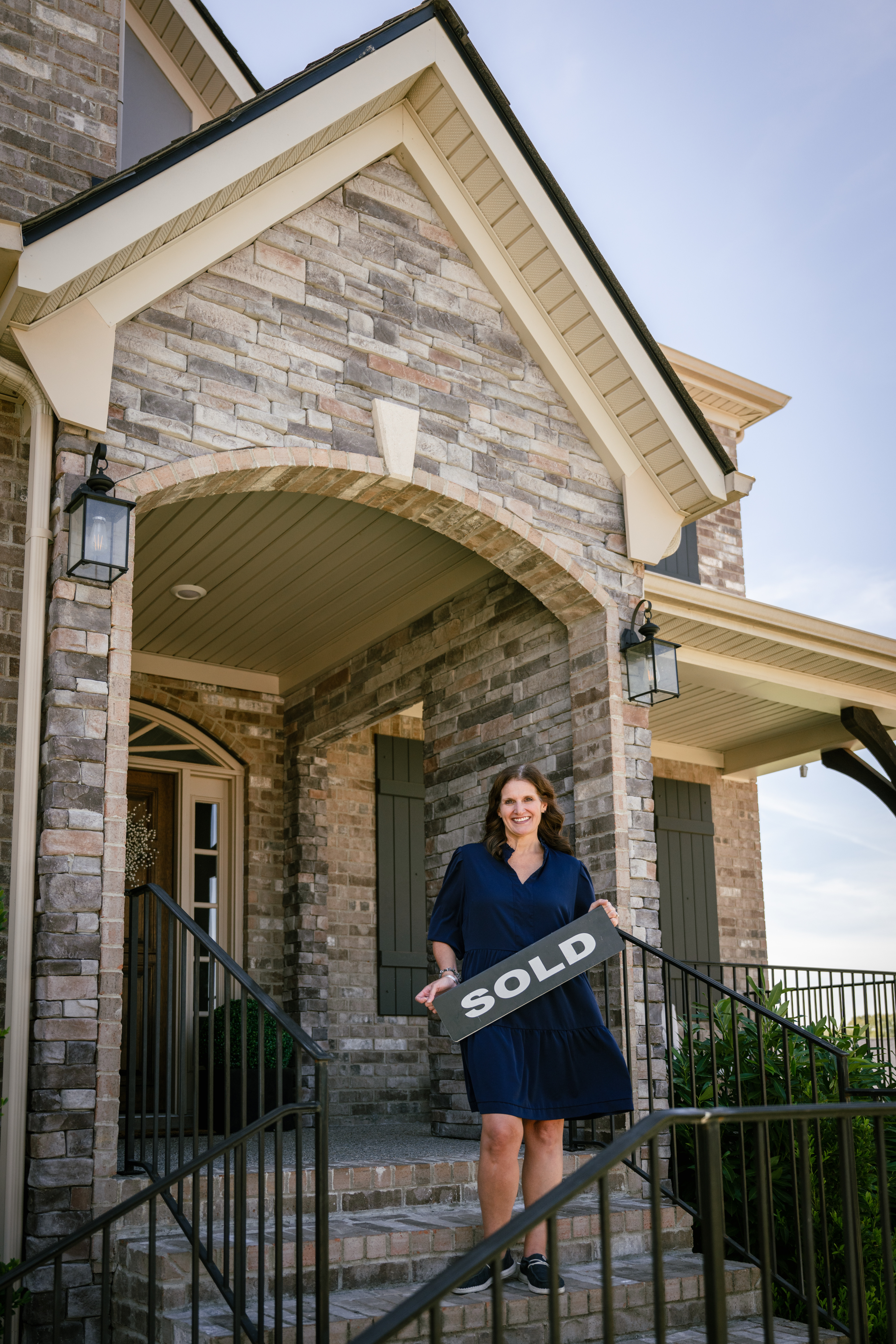 LeeAnn Kampfer holding a sold sign on a front porch